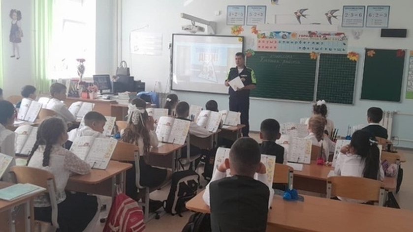 Дети в классе сидят за партами. Перед ними стоит ВРИО командира ОВ ДПС ГИБДД. Он ведет беседу. Ребята внимательно слушают